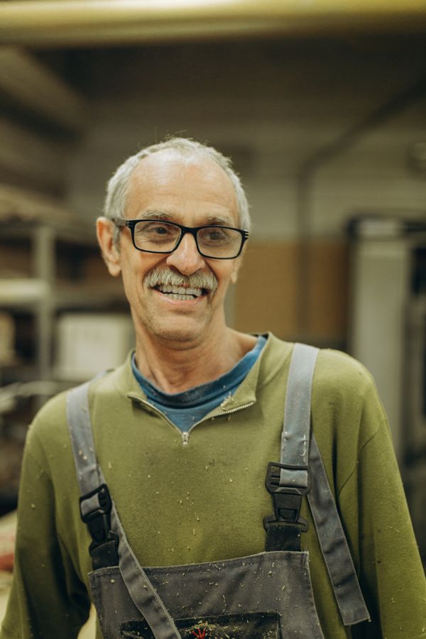 Fontanero veterano con mono de trabajo sonriendo en el taller