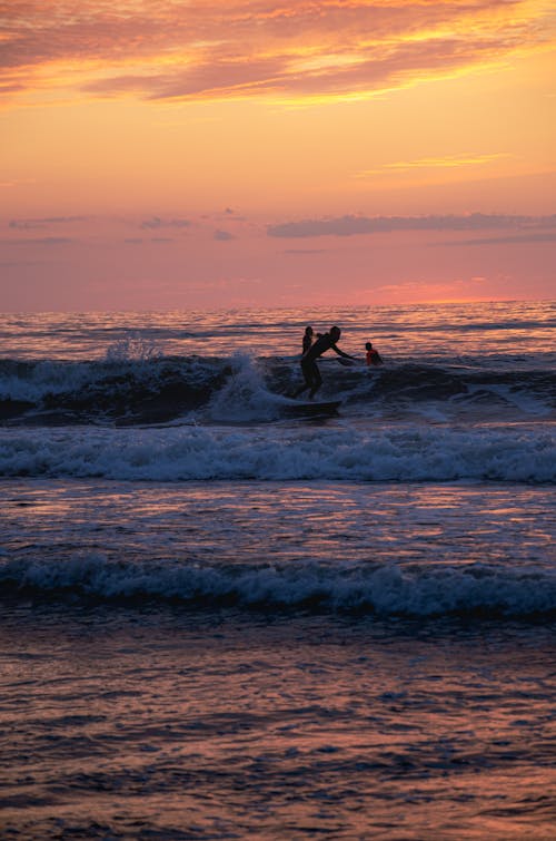Free Man Surfing on Sea Waves during Sunset Stock Photo
