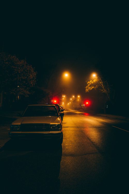 Free Atmospheric urban scene with parked cars under streetlights on a foggy night. Stock Photo