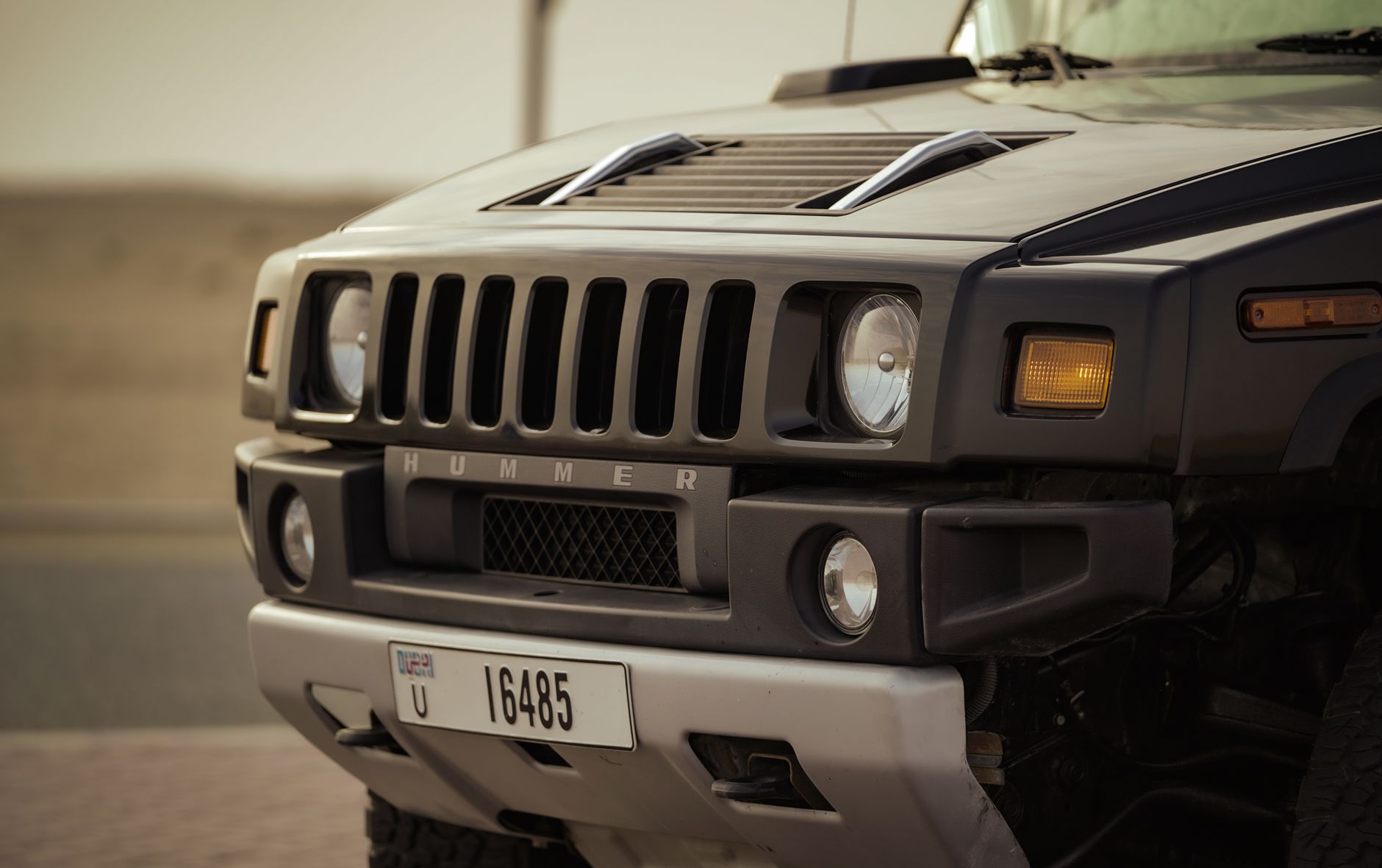 Detailed front view of a Hummer vehicle on a desert road, highlighting its robust design.