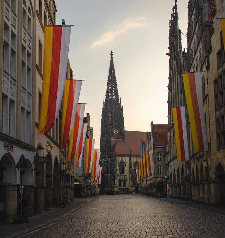 Banners Hanging On Buildings Along A Cobblestone Street