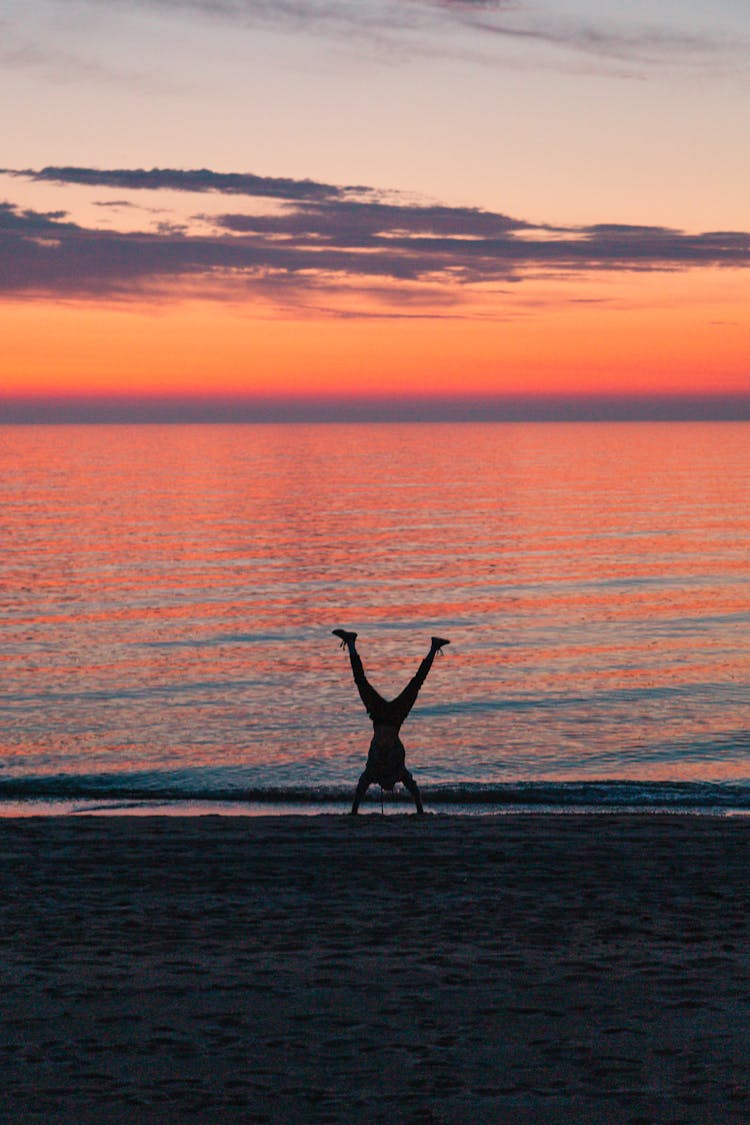 A Silhouette Of A Person Doing A Handstand