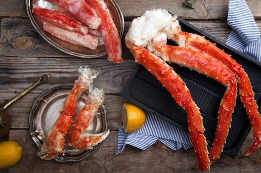 Delicious frozen and cooked King crab legs with lemon on a wooden background, ideal for seafood lovers.