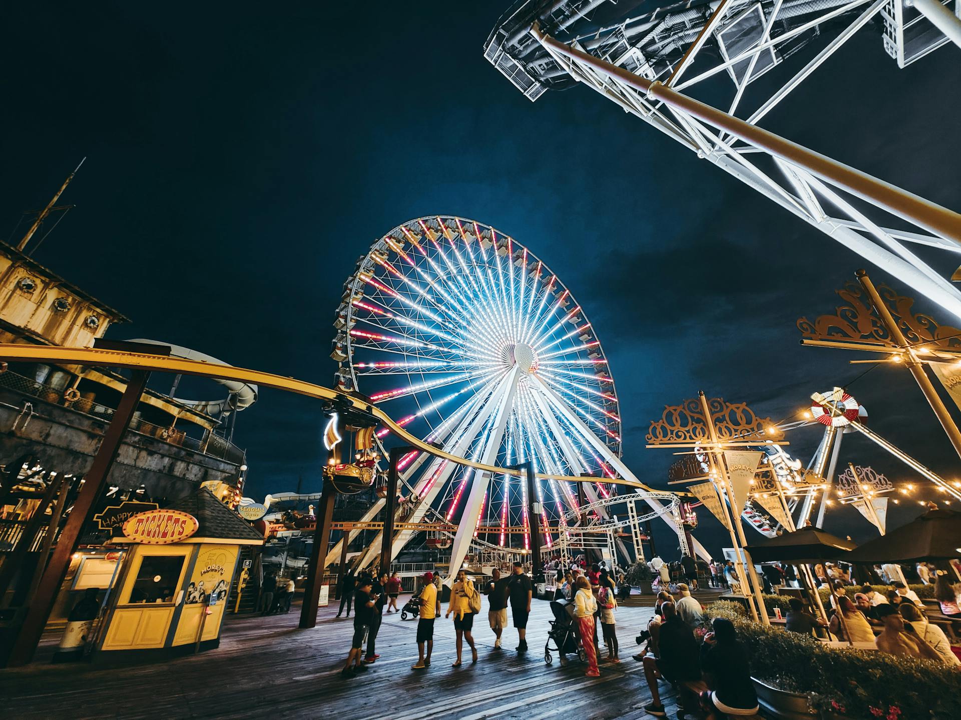 Lit-up Ferris wheel and rides at Wildwood amusement park in New Jersey at night.