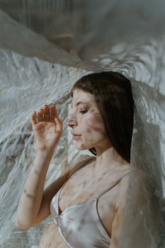 Captivating portrait of a brunette woman under a sheer lace veil, basking in gentle light.