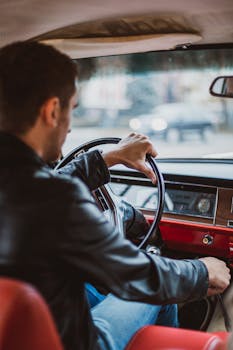A man drives a vintage car, showcasing a retro and stylish interior view.