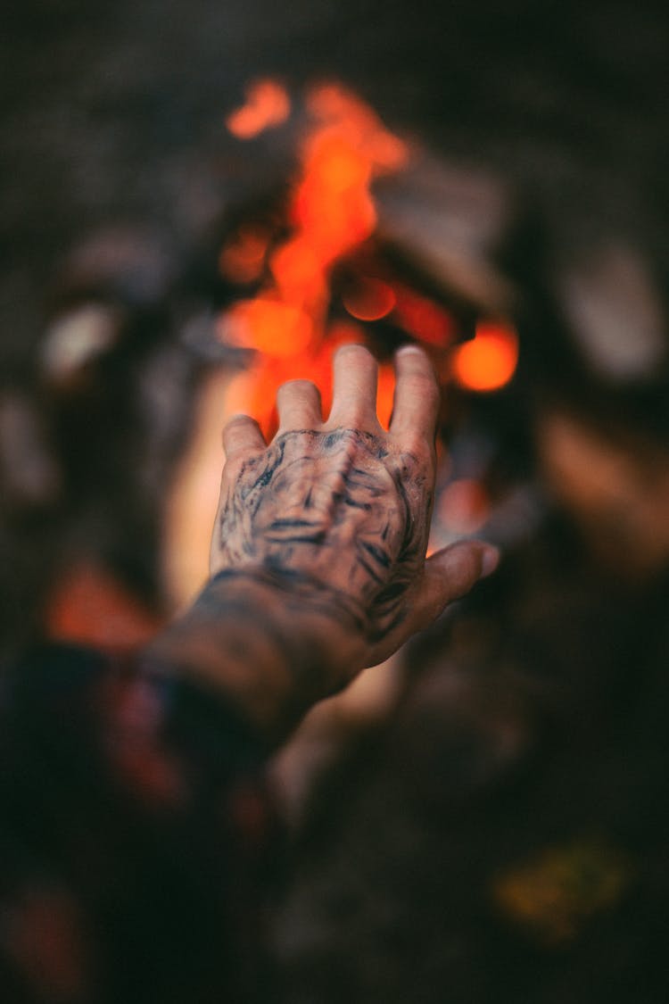 Close-up Of Hand With Tattoo Stretching To Fire