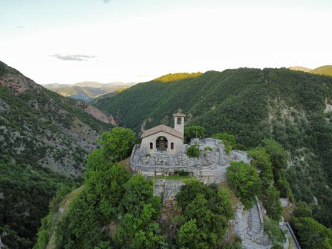 A stunning aerial view of a mountain church surrounded by lush greenery and distant peaks.