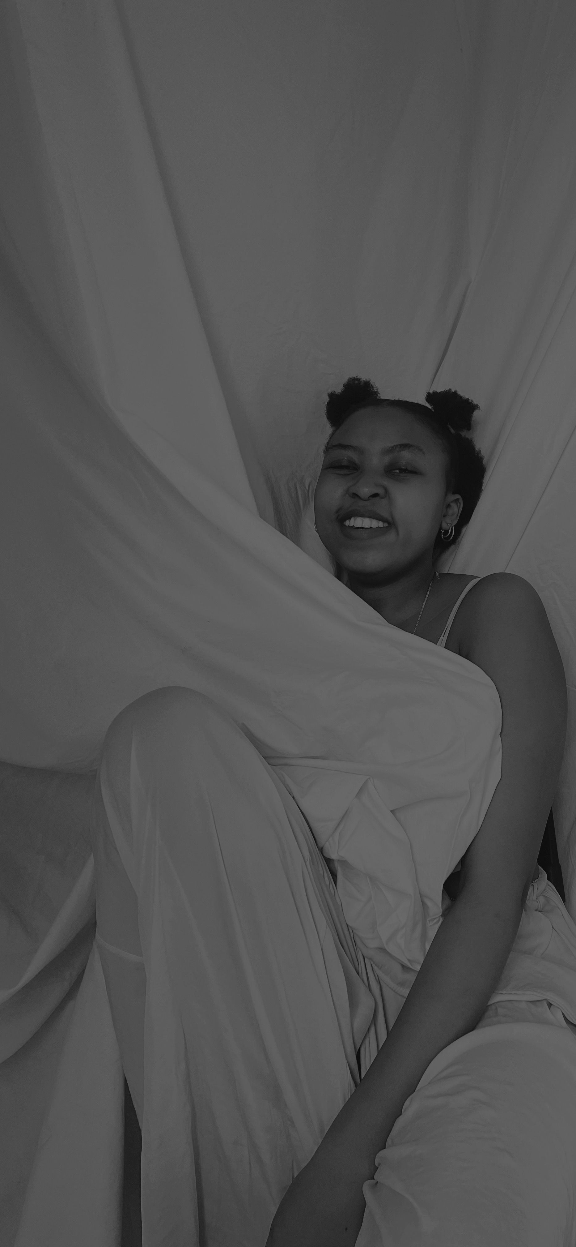 Black and white portrait of a woman smiling while comfortably reclining indoors with a relaxed expression.