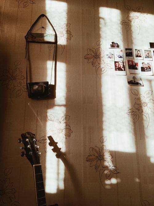 Free A cozy room featuring a guitar, vintage camera, and wall photos bathed in warm sunlight. Stock Photo