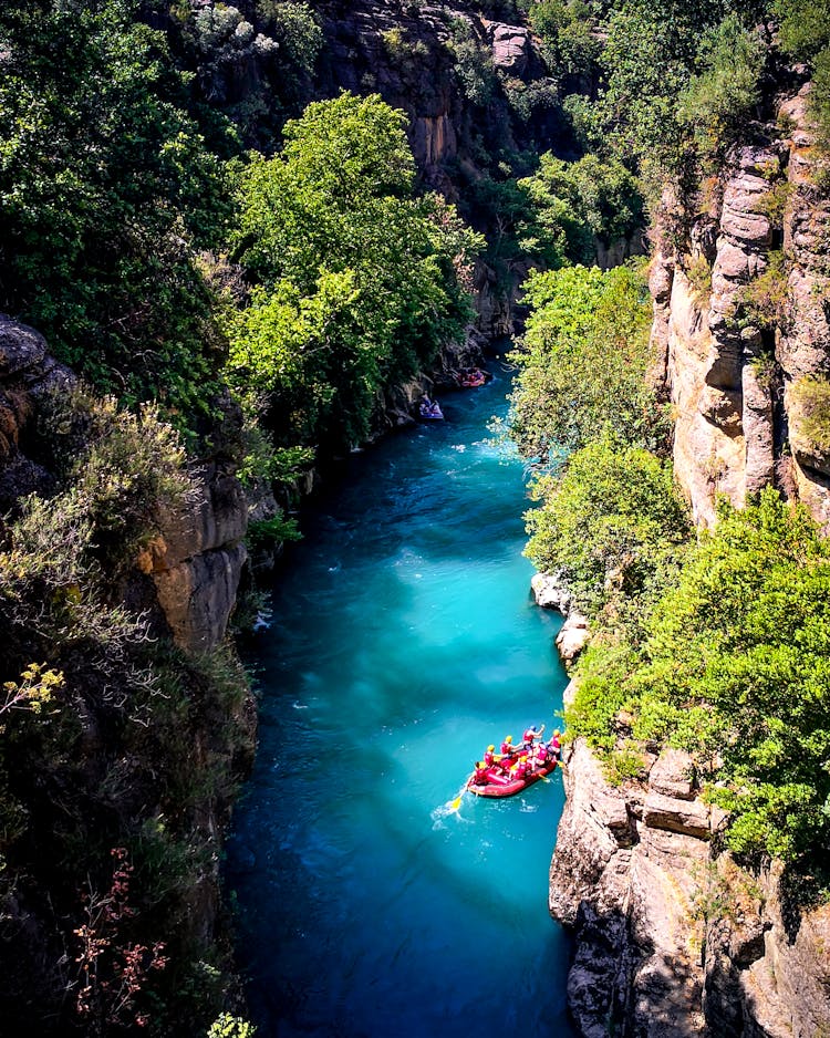 People Water Rafting On The River Between Rocky Mountains