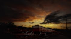 宁静的火车轮廓映衬着充满活力的日落天空和引人注目的云层