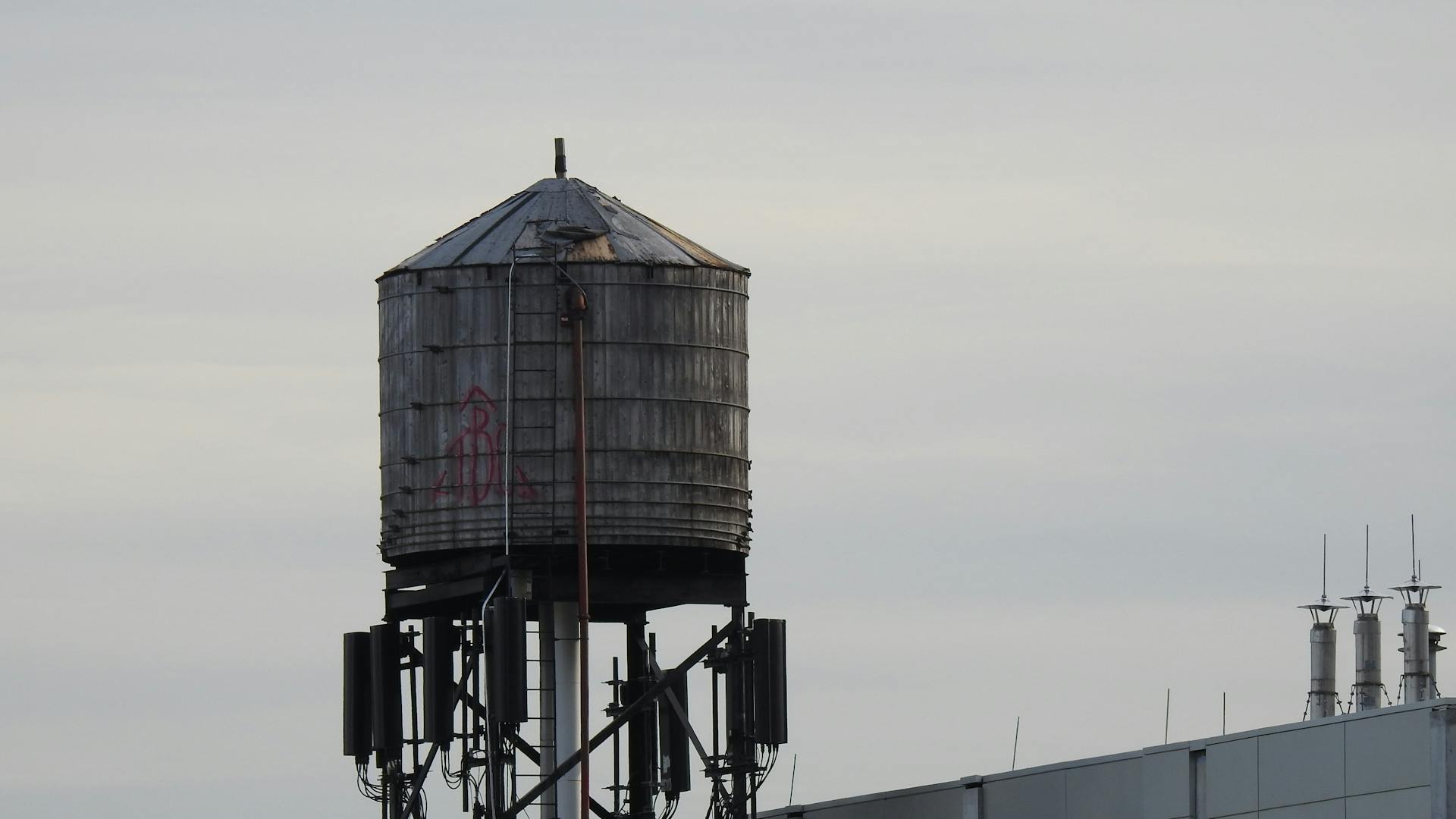 A metal water tank stands prominently on a rooftop against a clear sky.