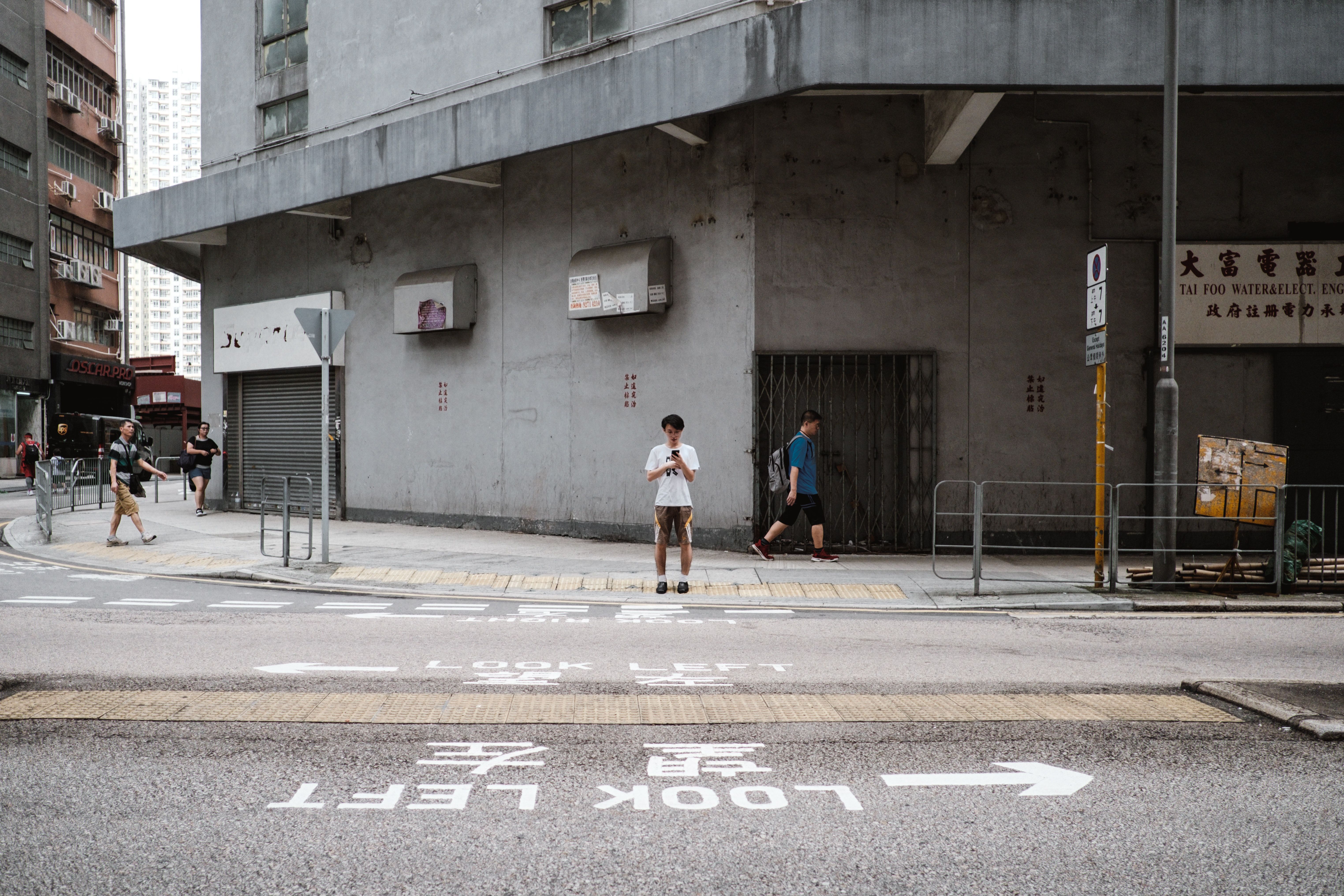 City street with pedestrians crossing, featuring urban architecture.