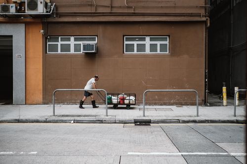 Free A man pulling a cart along a city street in Hong Kong, showcasing urban life and manual labor. Stock Photo