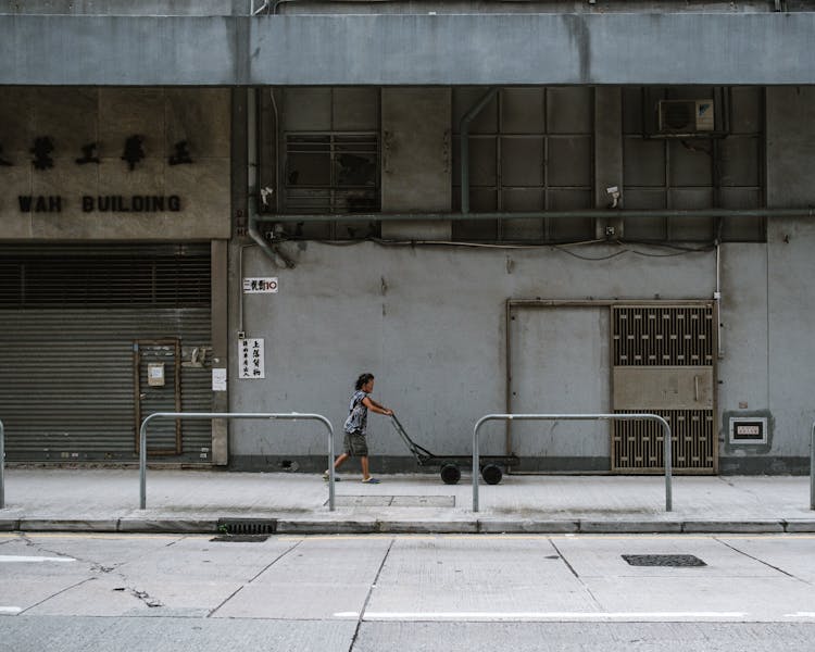 A Woman Pulling A Cart On The Street