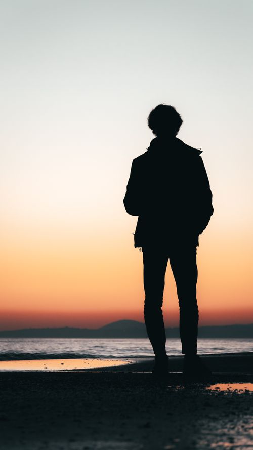 Free A silhouette of a person standing by the beach during a stunning sunset in Punta del Este, Uruguay. Stock Photo