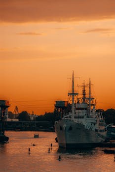 A serene sunset view of a harbor in Kaliningrad, Russia, showcasing a ship docked on calm waters.