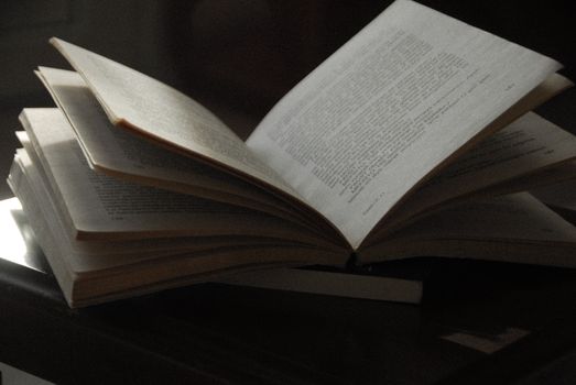 A close-up of an open book with visible text, placed on a dark wooden surface. Ideal for reading-themed content.