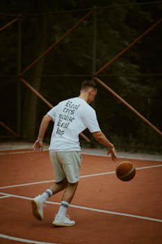 A young man dribbles a basketball on an outdoor court in Chisinau, showcasing casual athleticism.