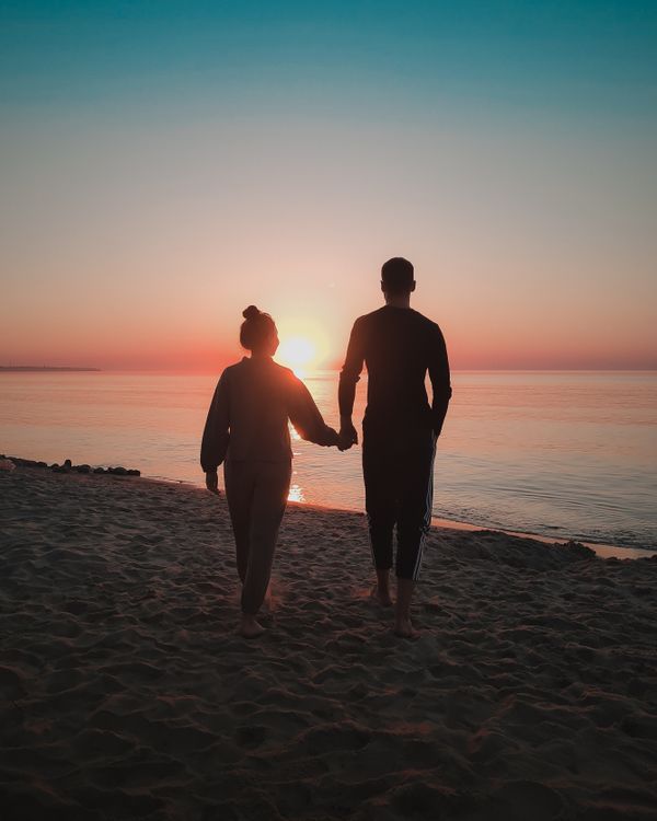 Silhouette of a Couple Holding Hands at a Beach · Free Stock Photo