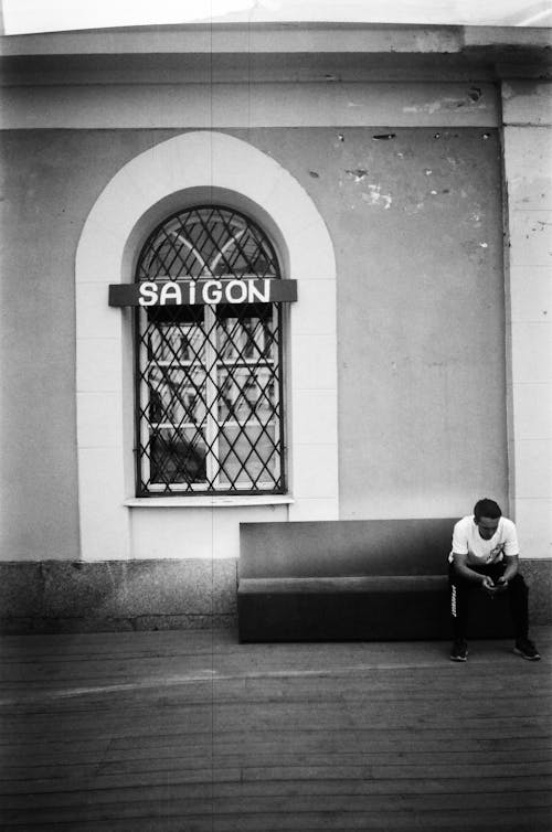 Grayscale Photo of a Man Sitting on Bench