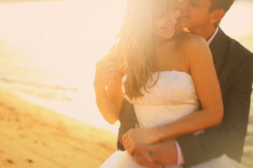 Photo of a Man Hugging a Woman in a White Gown