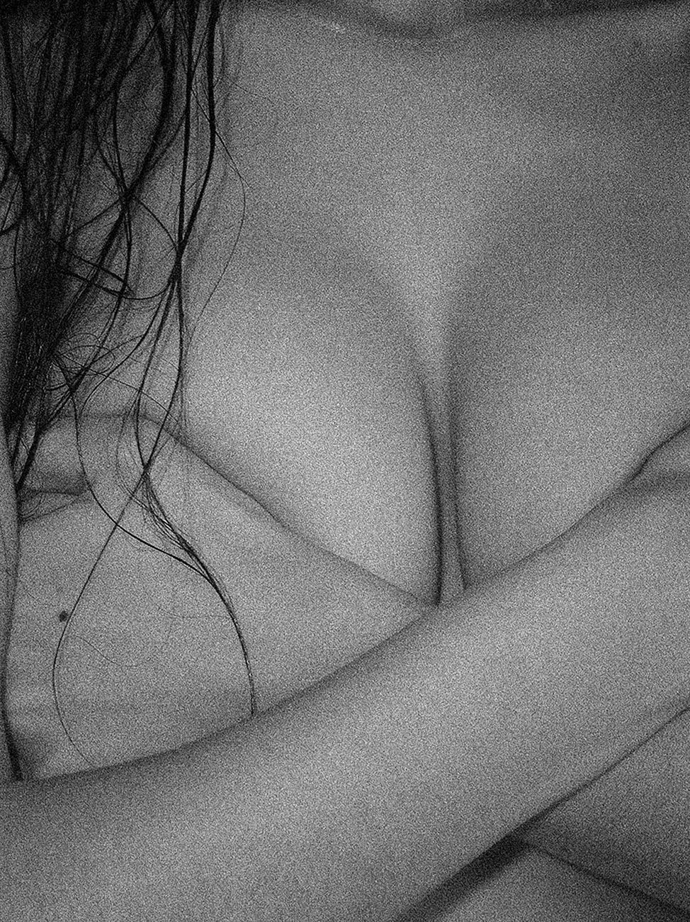 Artistic monochrome close-up of a woman's crossed arms with covered upper body.