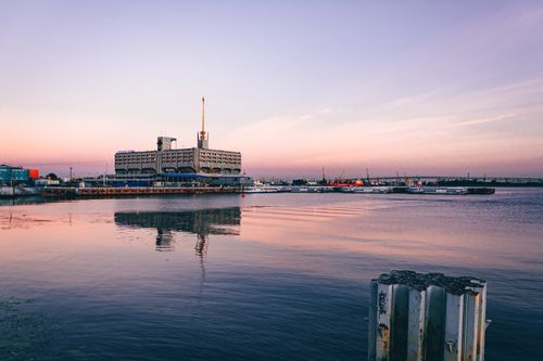 Free A serene view of a harbor at twilight with urban buildings and ships reflecting on the calm sea Stock Photo