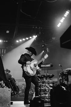 Black and white photo of a man playing guitar on a concert stage.