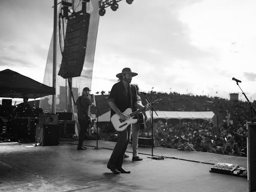 Man in Black Hat Playing Guitar on Stage