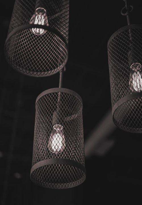 Free Close-up of rustic pendant lamps with mesh cages, creating a moody, industrial ambiance. Stock Photo