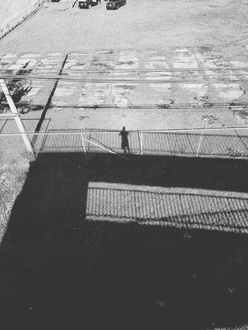 Grayscale Photo of a Shadow of a Person on a Concrete Road