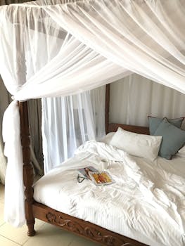 A serene and inviting four-poster bed with a sheer canopy, capturing a peaceful and cozy atmosphere.
