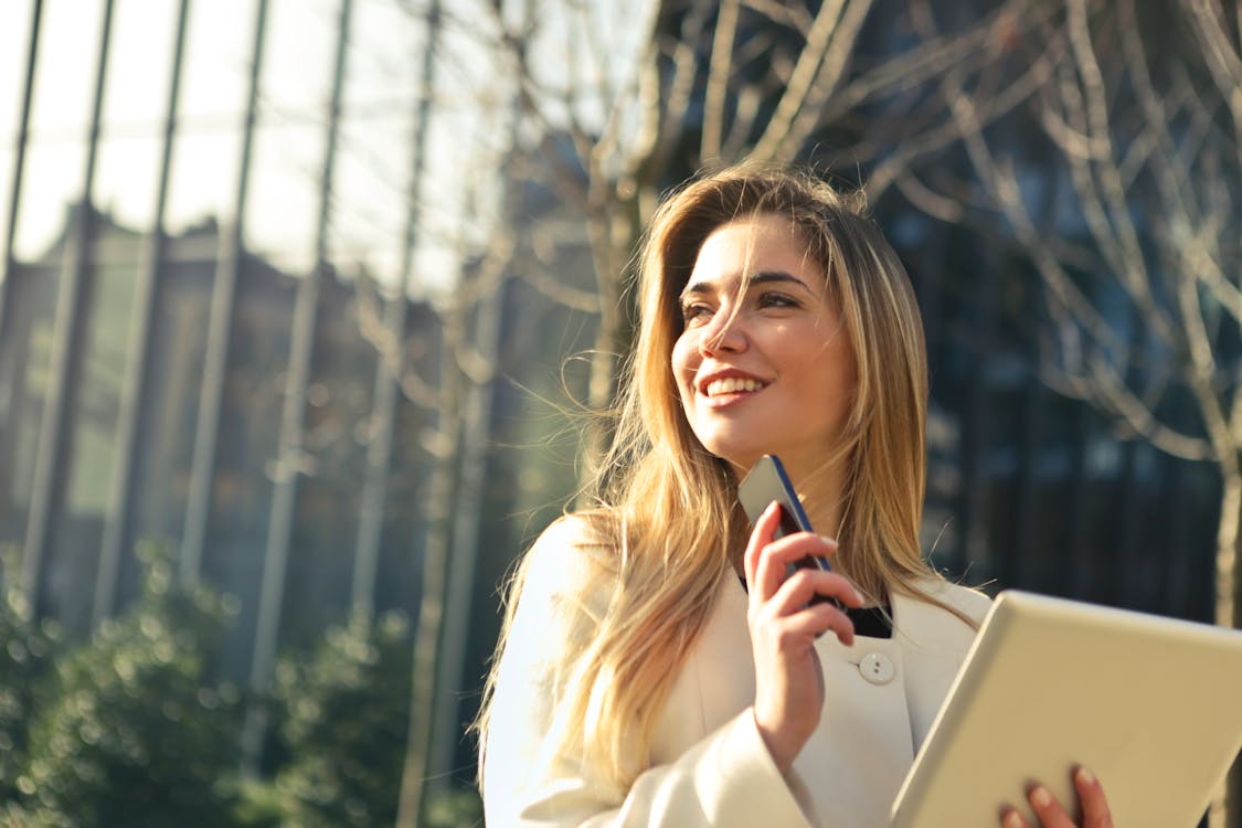 Free 女人穿着白色上衣，拿着智能手机和平板电脑 Stock Photo