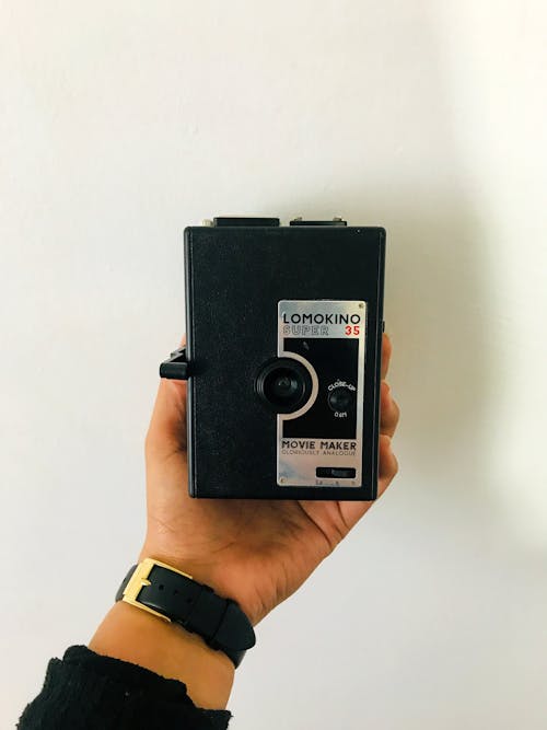 Photo of a Person's Hand Holding a Black and Silver Camera