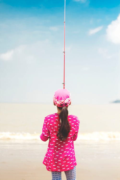 無料 赤い釣り竿を保持しているピンクの長袖シャツの女性 写真素材