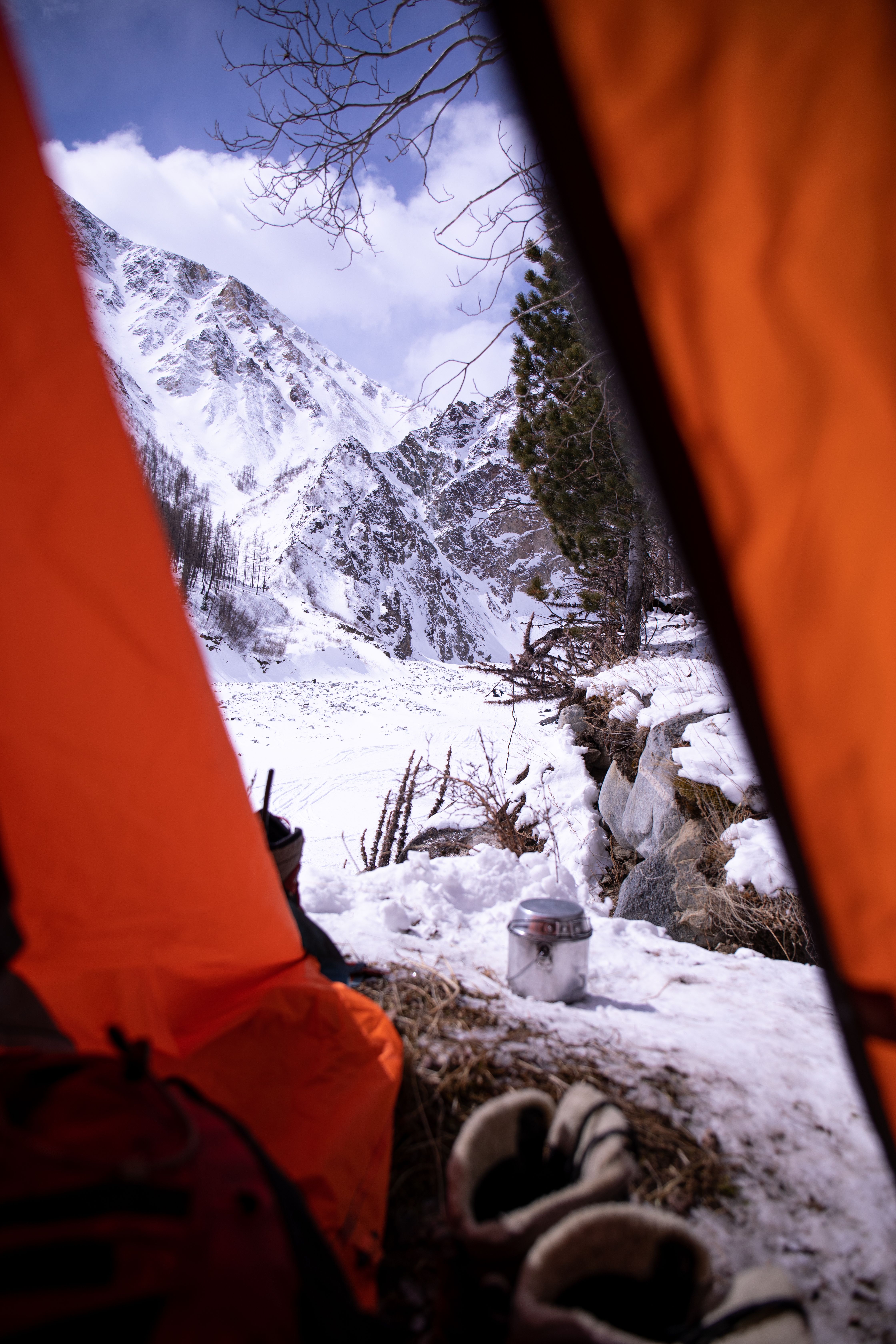 Winter campsite pitched below snow-covered hills, the kind of country where the ground robs heat long before the air does