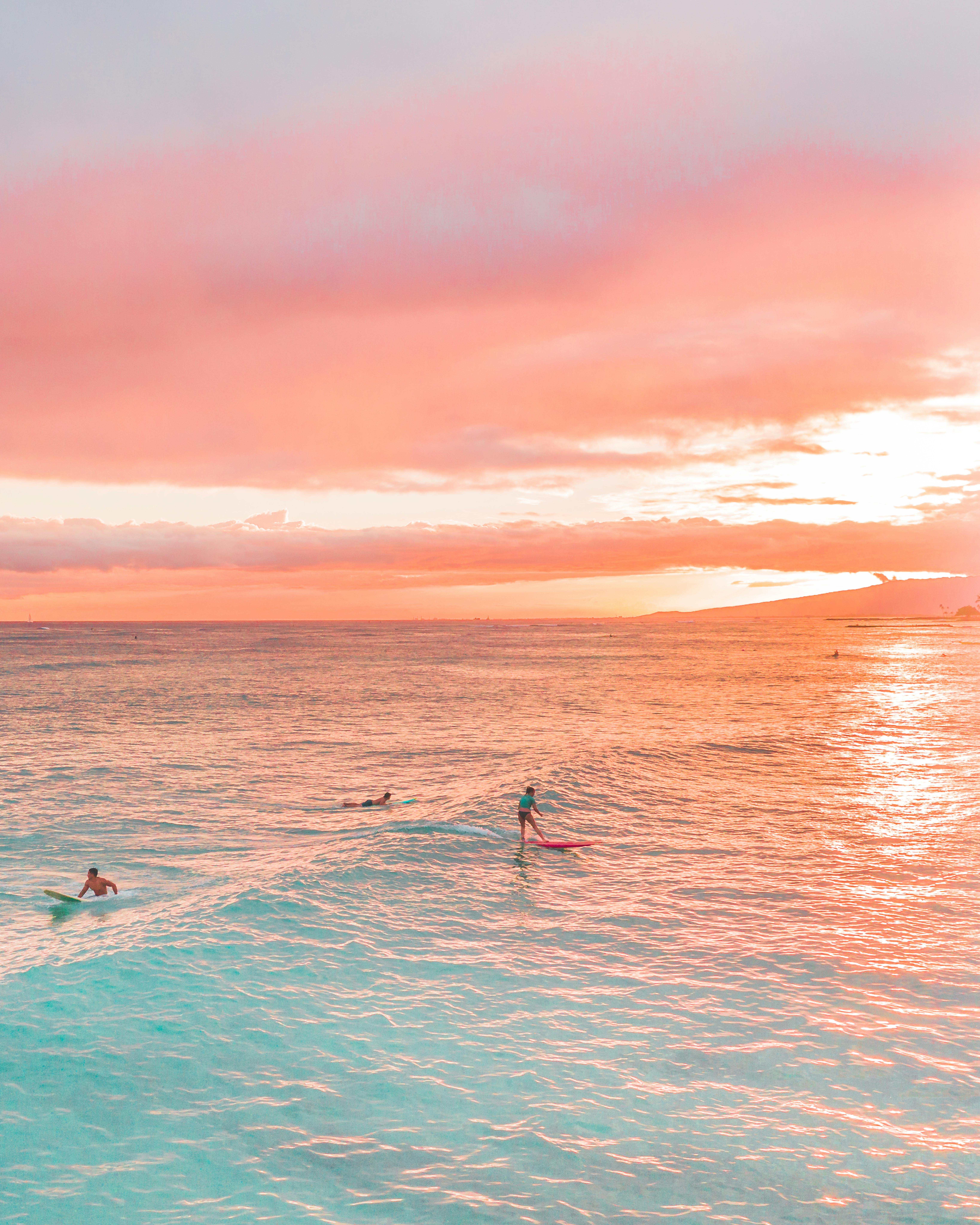 冲浪者在海边令人惊叹的粉红色日落中乘风破浪