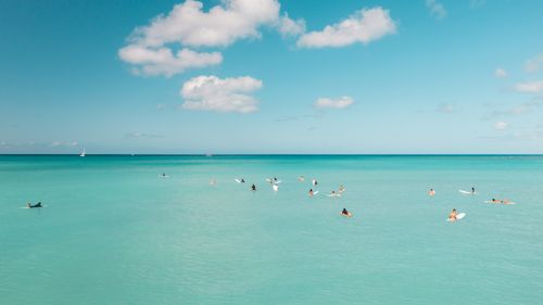 Free Adults enjoy surfing in turquoise waters under a clear blue sky. Perfect leisure and recreation scene. Stock Photo