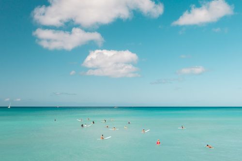 Free A vibrant day at the beach with surfers enjoying the azure waves and clear skies. Stock Photo