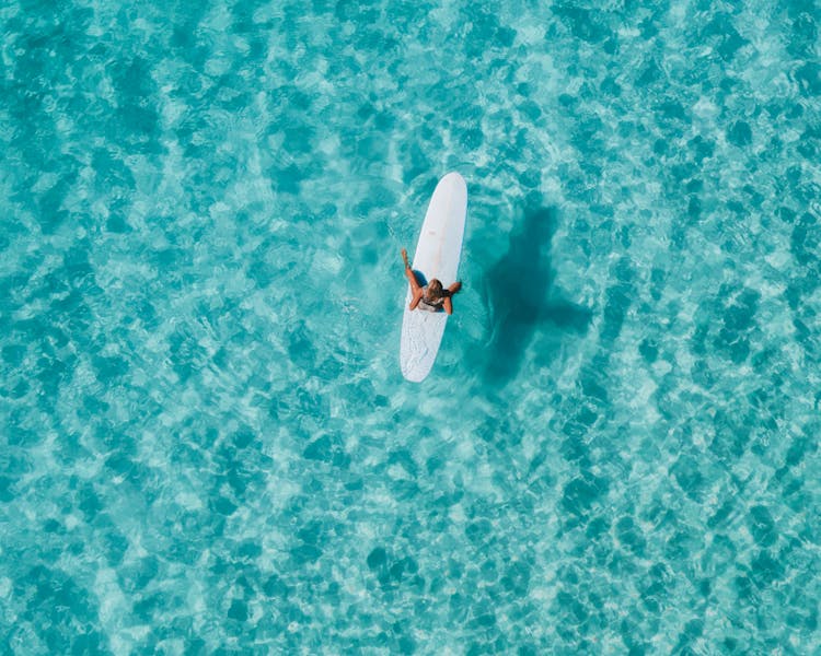 A Woman Sitting On A Surfboard