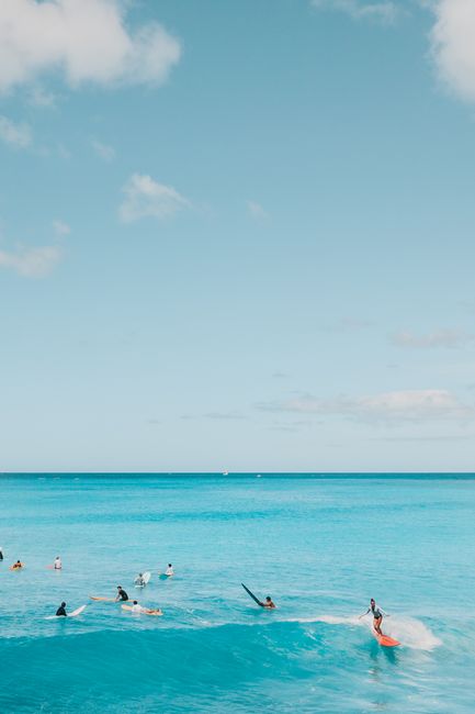 A group of surfers ride the turquoise waves under a clear blue sky, capturing the essence of beachside adventure.