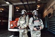 Man in Gray and White Suit Wearing Gas Mask Holding Orange and White Power Tool