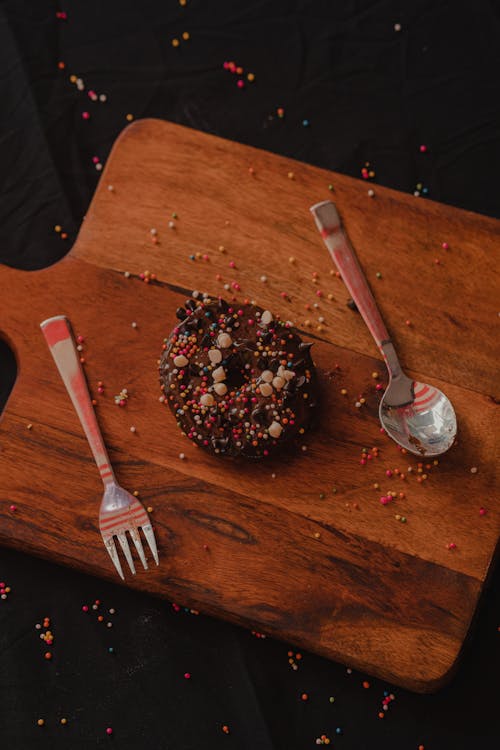 Free Overhead Shot of a Chocolate Donut on a Wooden Chopping Board Stock Photo