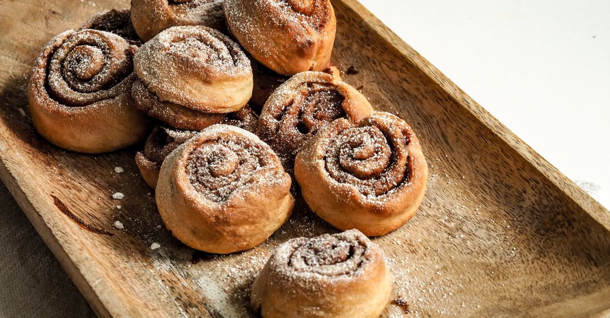 A batch of freshly baked cinnamon rolls dusted with sugar on a wooden tray. - Evidence evidence guide for cinnamon appetite randomized trial