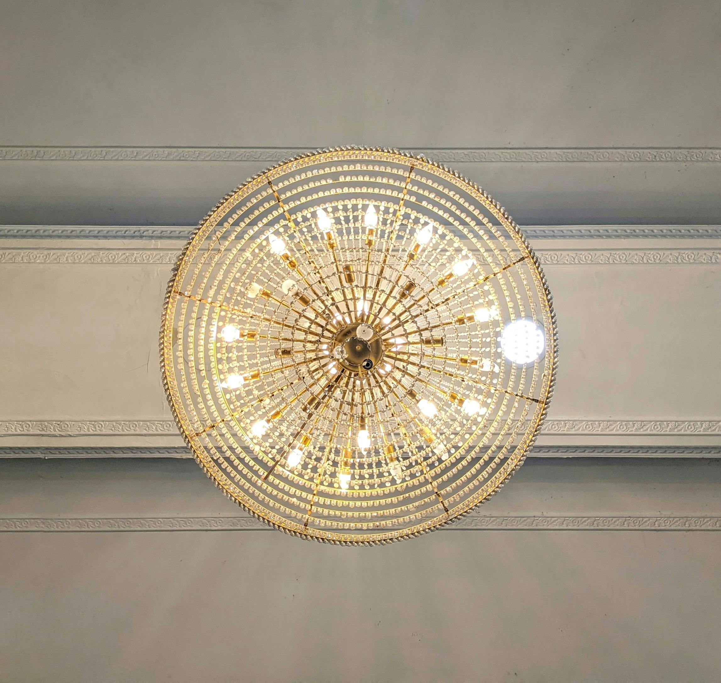 A luxurious crystal chandelier illuminated against a decorated ceiling, showcasing elegance.