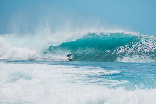 A Person in Blue Wetsuit Surfing in the Ocean