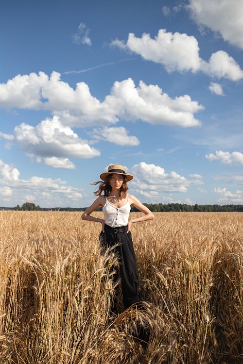 Woman in a Straw Hat on a Wheat Field in Summer 
