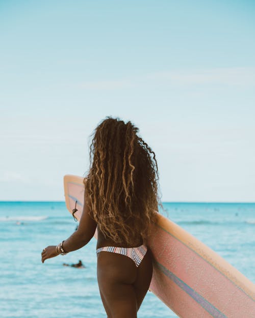 Back View of a Woman Walking While Holding Her Surfboard
